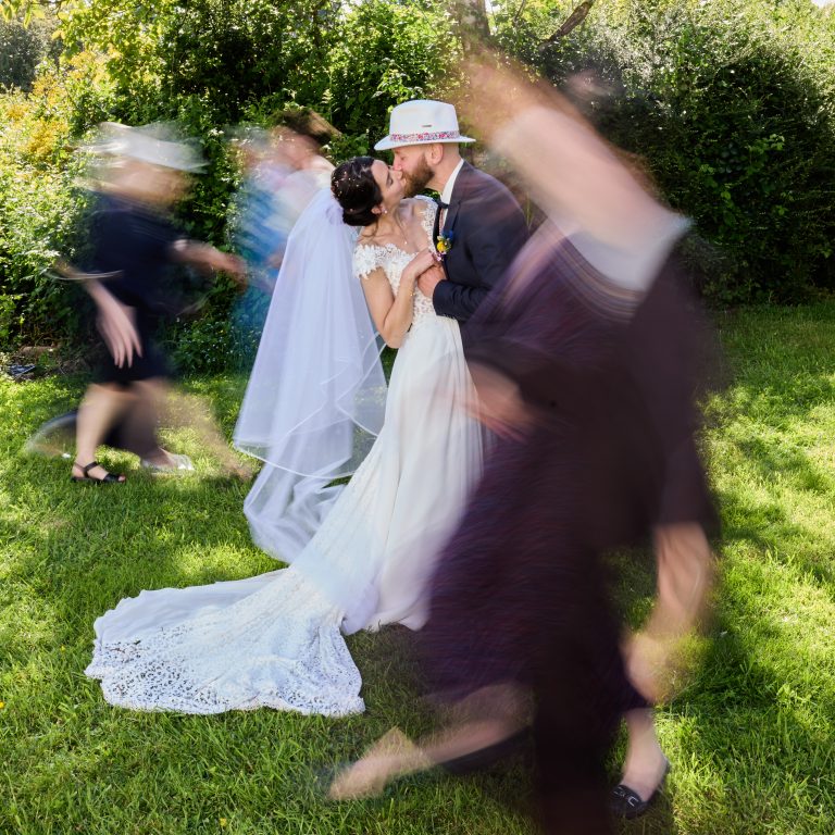 Mariés s’embrassant entourés d’une ronde festive de leurs invités lors d’un mariage en Bretagne.